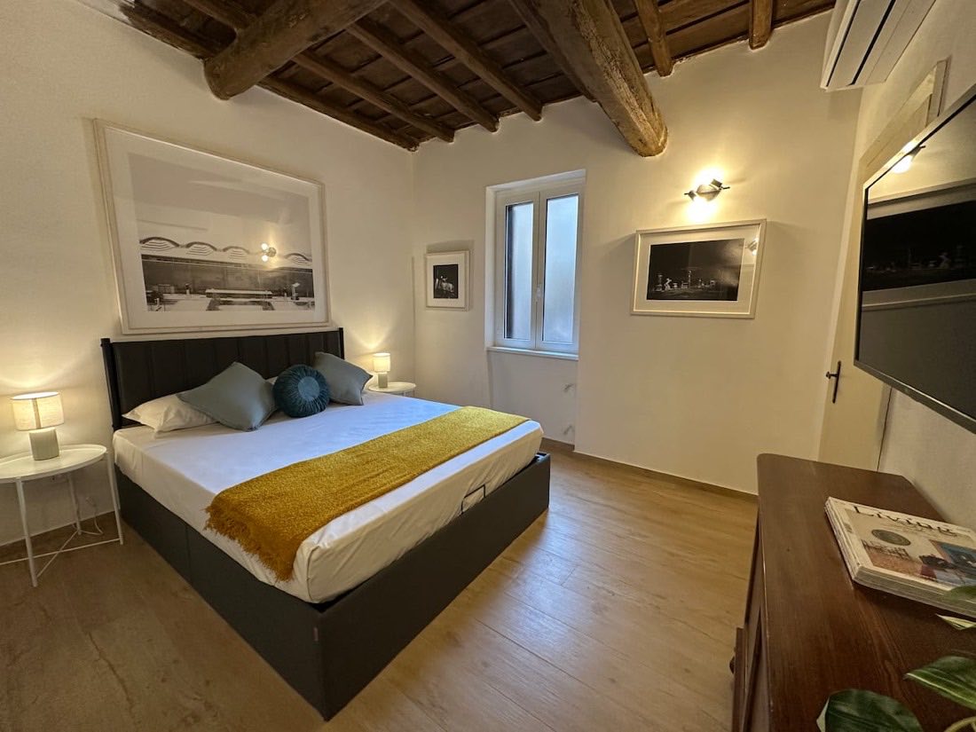 Camera da letto con travi a vista di un appartamento appena ristrutturato a Trastevere
